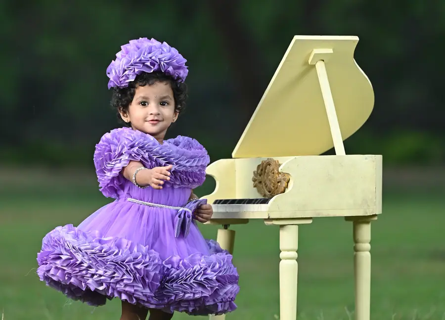 Child birthday portrait with a piano prop in a green outdoor setting