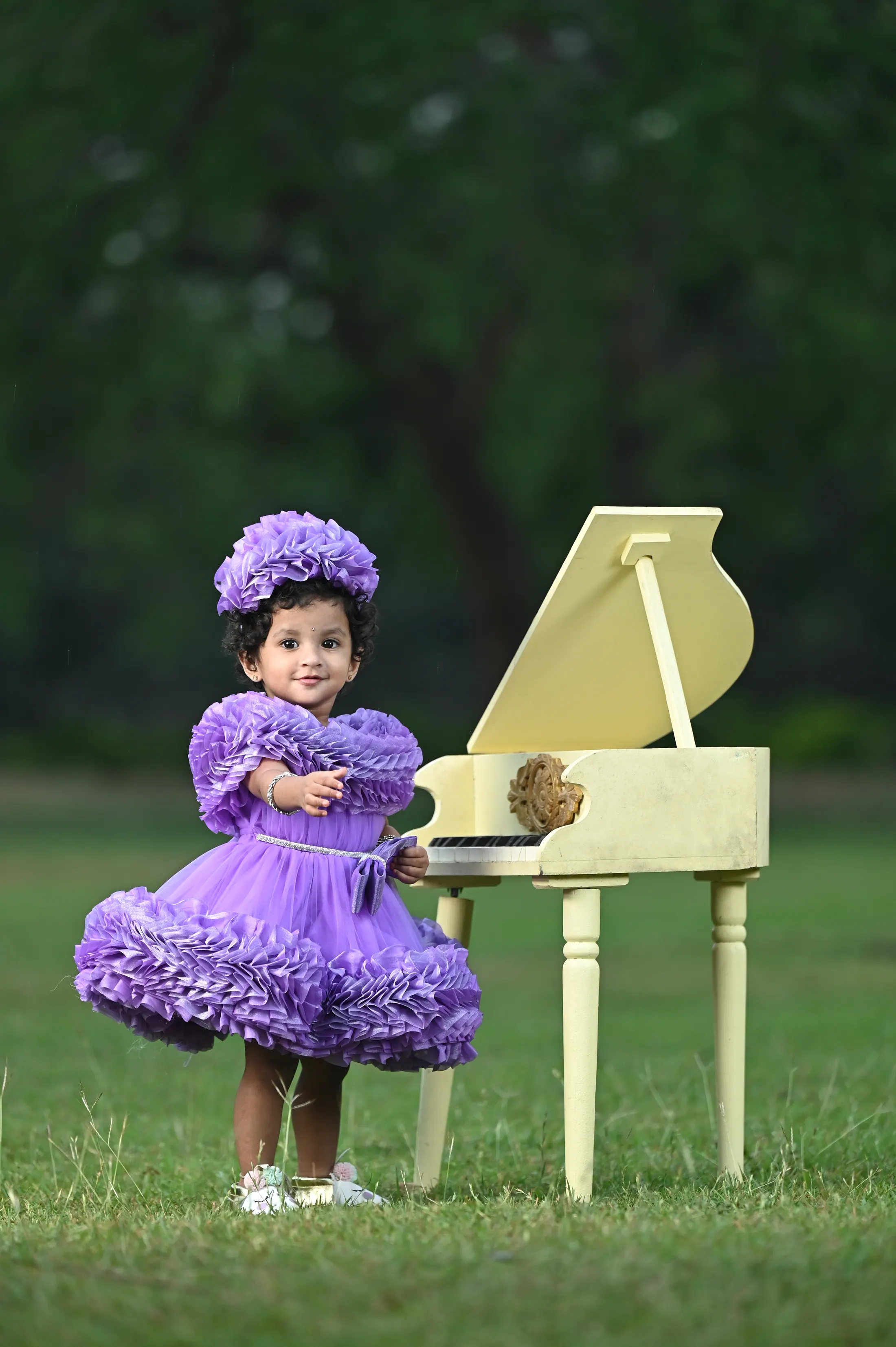 Child birthday portrait with a piano prop in a green outdoor setting