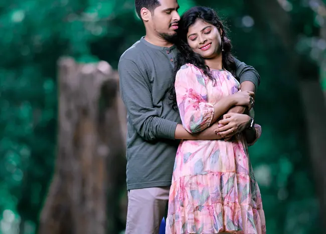 Pre-wedding couple embracing among tall trees