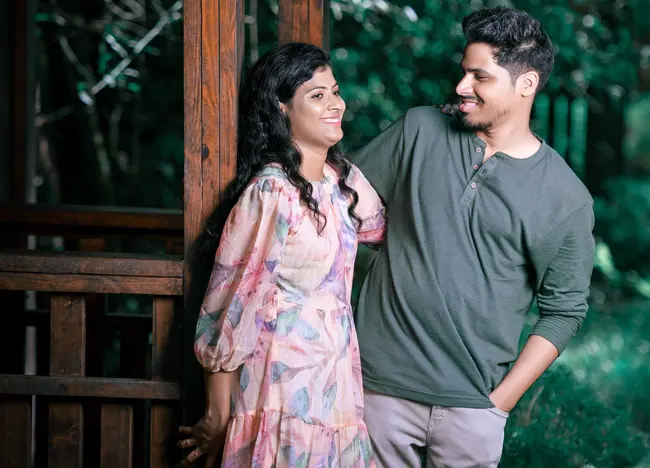 Pre-wedding couple standing by a wooden cabin in green surroundings
